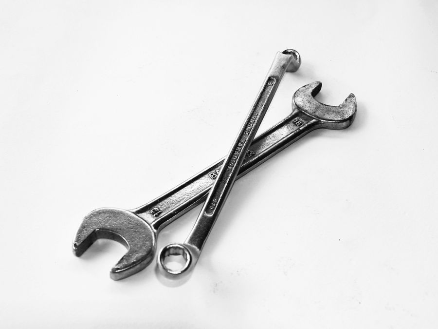 Two wrenches crossed on a plain surface, styled to represent ongoing upkeep.